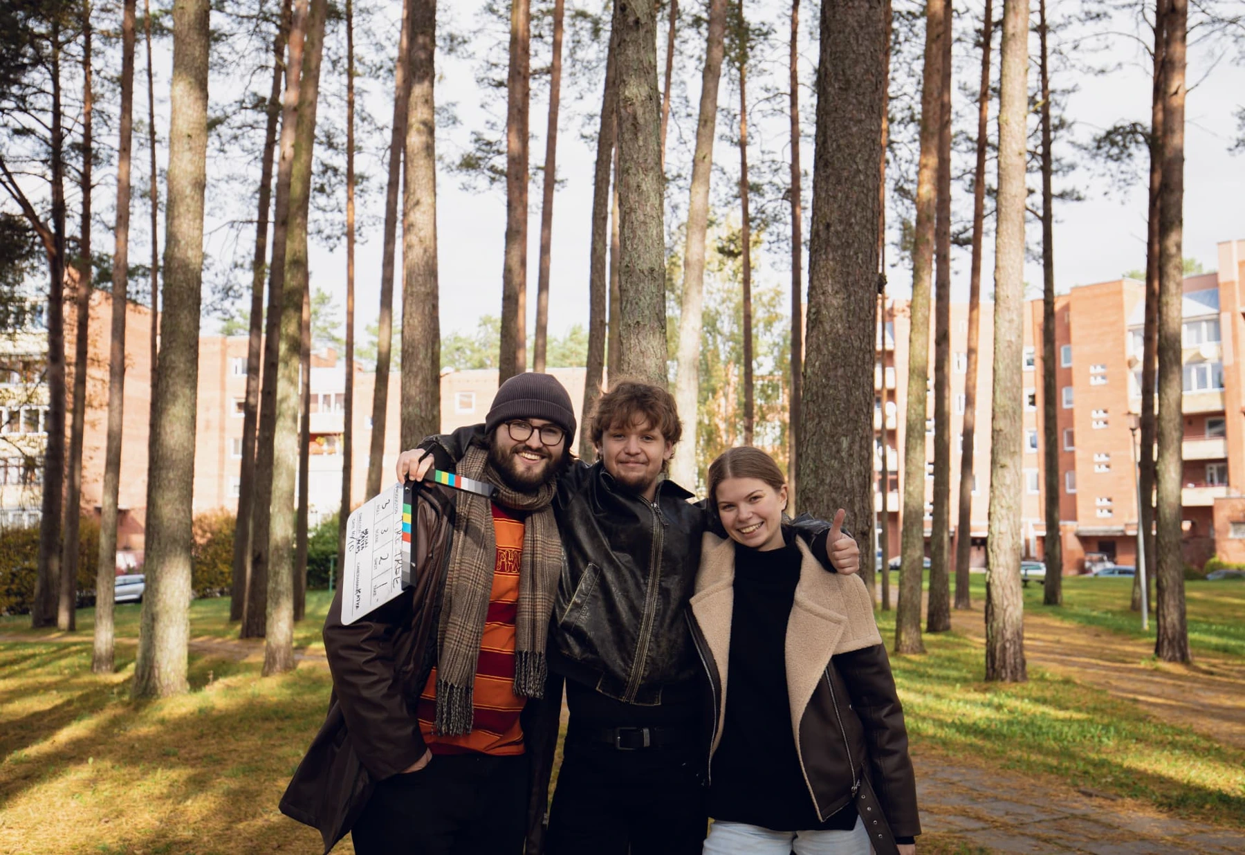 Three Film Camp participants posing with a clapperboard among pine trees