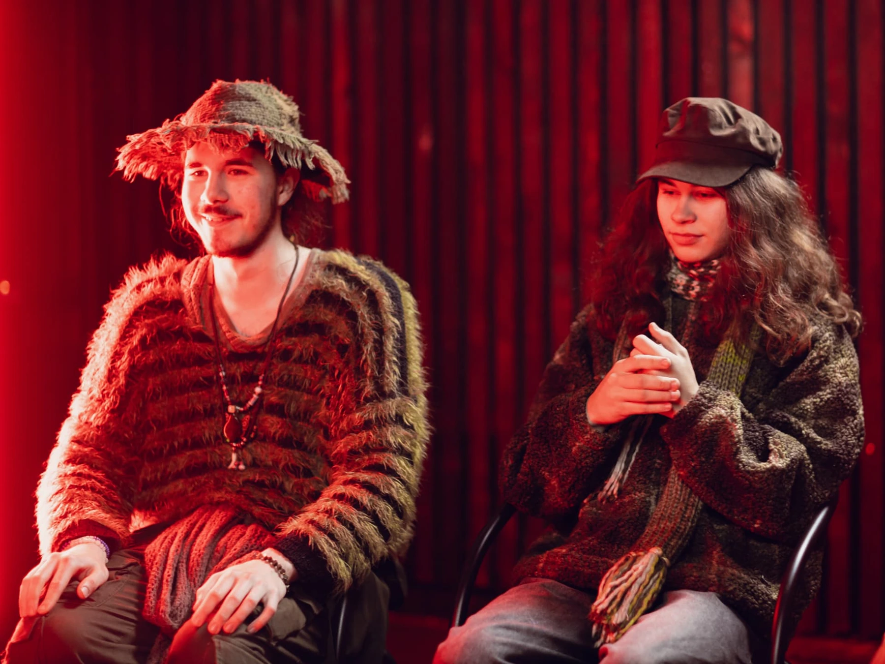 Two Film Camp participants in costumes seated in front of red curtains