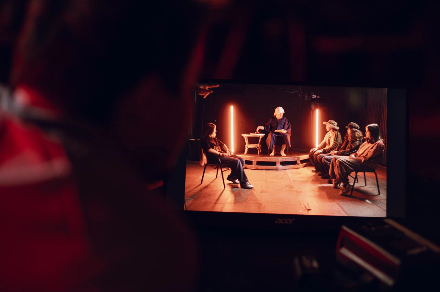 Behind the scenes at Film Camp: a monitor showing performers on a set with red lighting