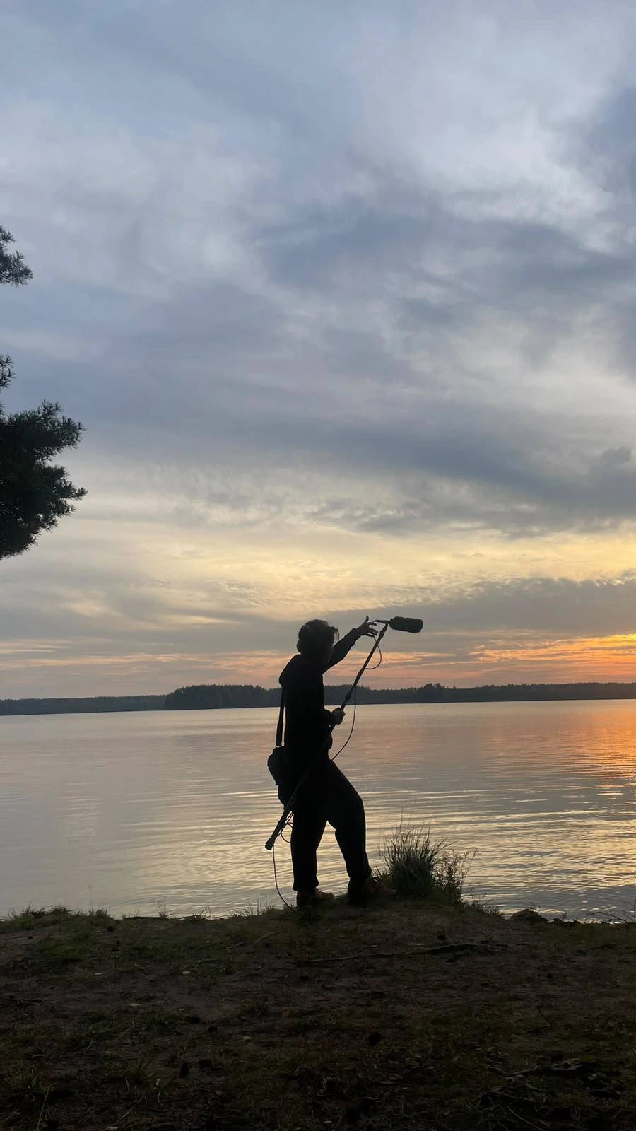 Film Camp sound recordist holding a boom microphone by the lake at sunset